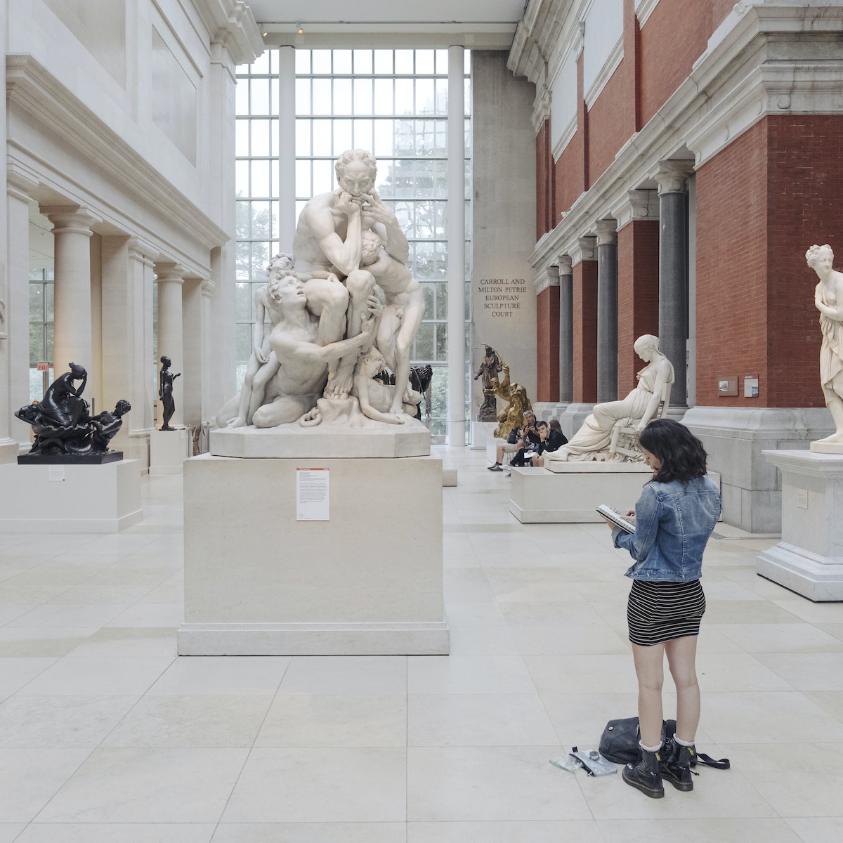 A woman takes notes in front of a sculpture at The Metropolitan Museum of Art.